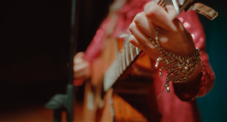 Primer plano de la mano de Naty Borda en el mástil de la guitarra, con pulseras de pedrería