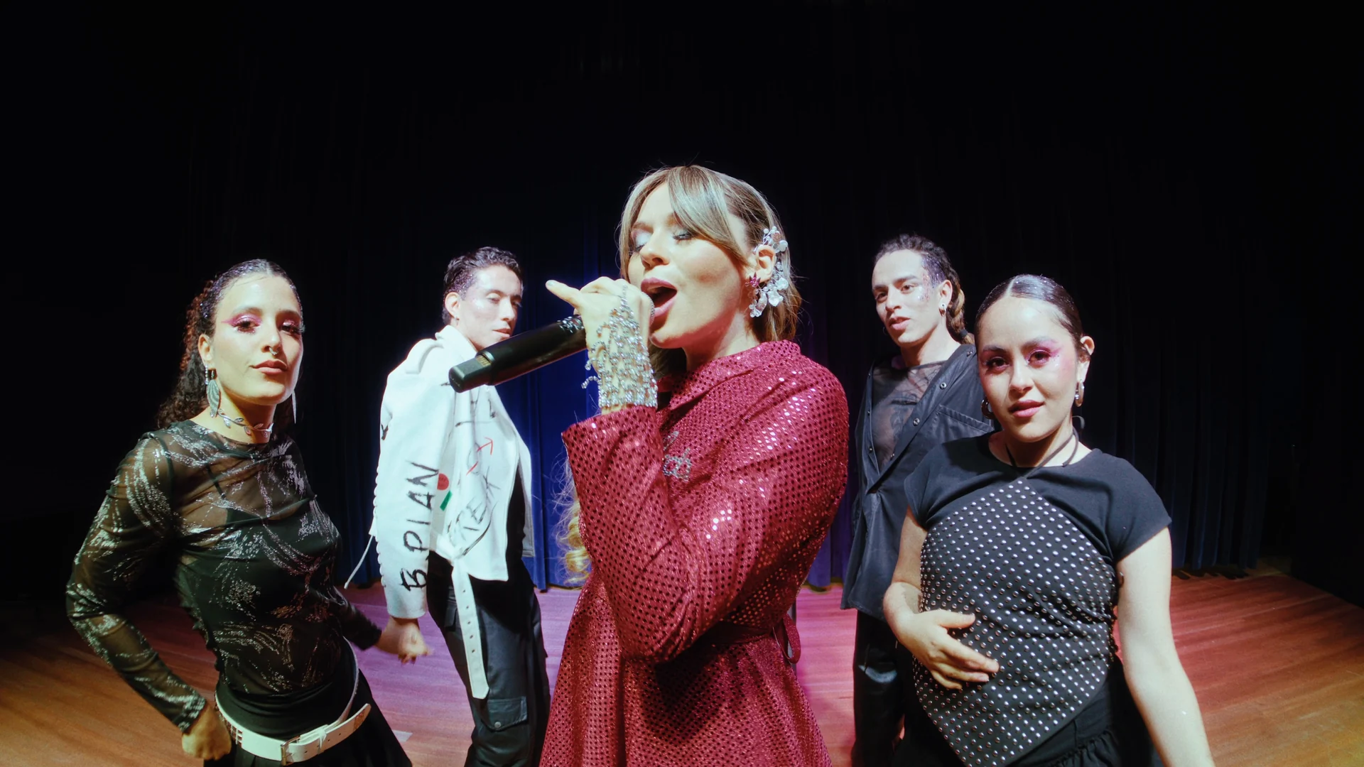 Naty Borda cantando frente a cuatro de sus bailarines