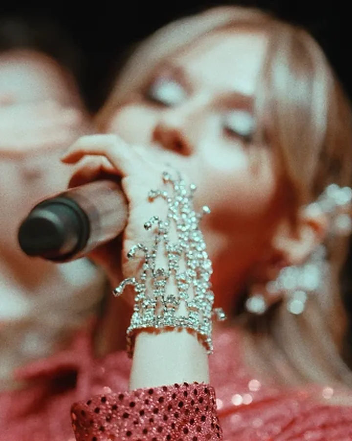 Naty Borda cantando, con un guante de pedrería en la mano del micrófono